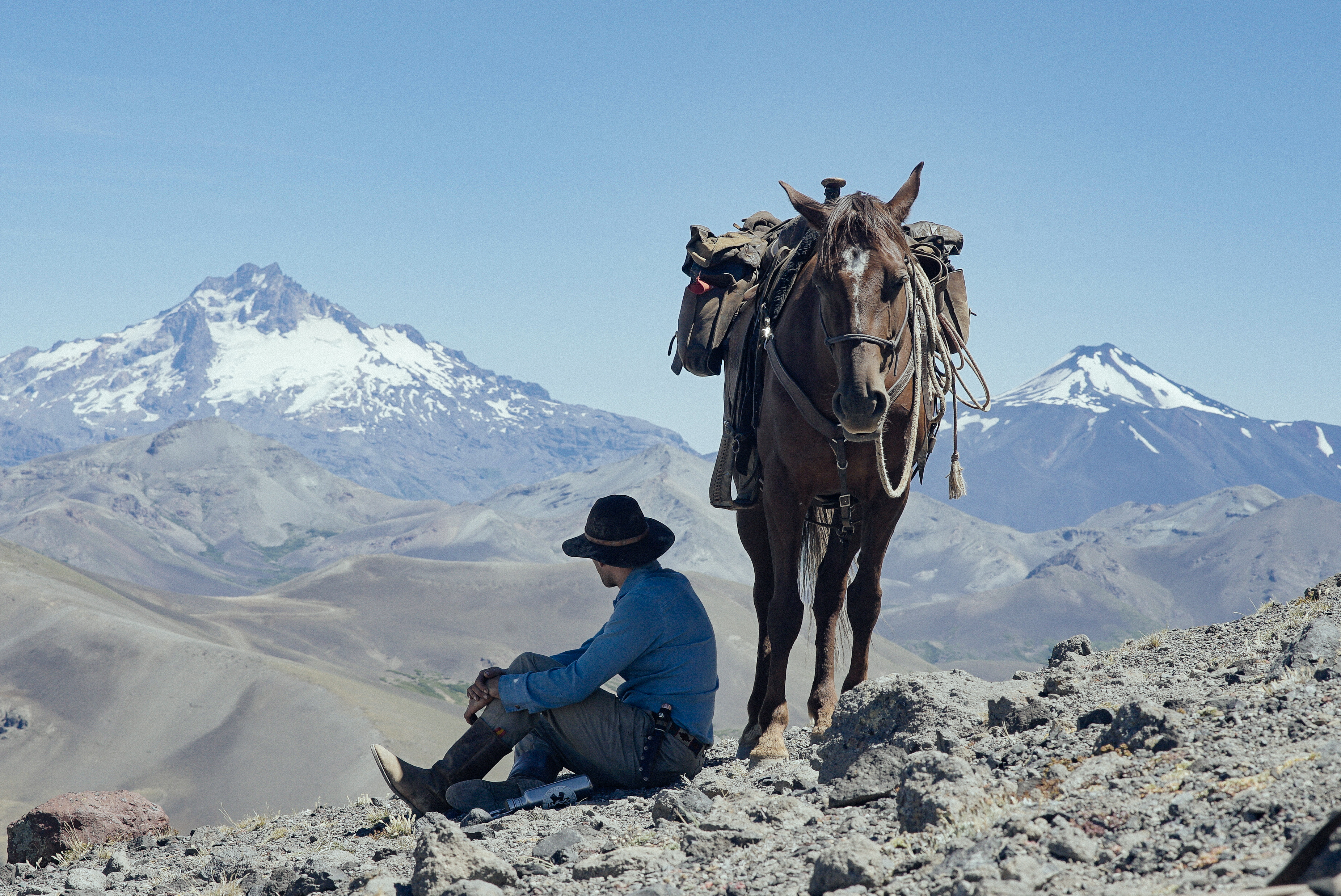 Man and horse overlooking snow capped peaks on mountain pass at Estancia Ranquilco in Patagonia Argentina