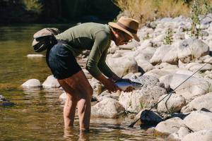 Fisherwoman catching a rainbow trout in the river at Estancia Ranquilco