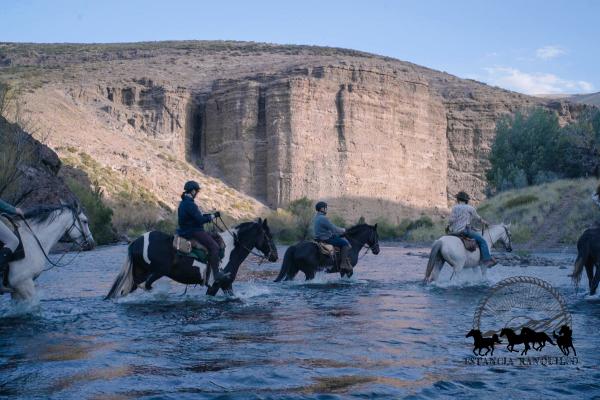 Riders on horseback crossing the river on the approach to Estancia Ranquilco in Patagonia Argentina
